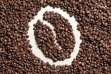 Close-up top view of coffee bean symbol made from roasted coffee grains on table