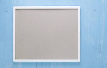 Fototapeta premium Blank photo frame on blue wood background. Painted scraped wooden board. Grunge plywood texture or pattern.