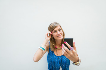 Naklejka premium Cute girl using cellphone in front of a white wall - facade.