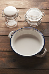 Vertical studio shot of empty glass jars and a plate on brown wooden table.