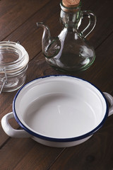 Vertical studio shot of empty glass jars and a plate on brown wooden table.