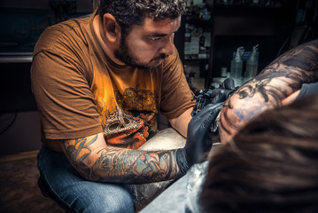 Professional tattooer makes cool tattoo in tattoo parlor