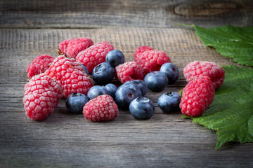Fresh raspberries and blueberries on wooden table