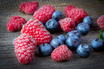 Fresh raspberries and blueberries on wooden table