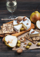 Camembert cheese with walnuts, honey and pears on rustic table. Glass of white wine © voloshin311
