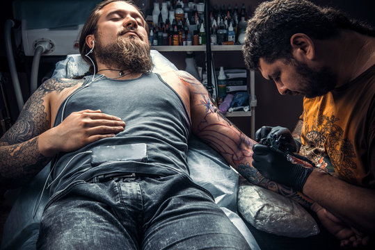 Professional tattooer create tattoo in tattoo studio