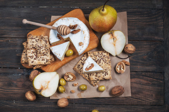 Camembert cheese with walnuts, honey and pears on rustic table