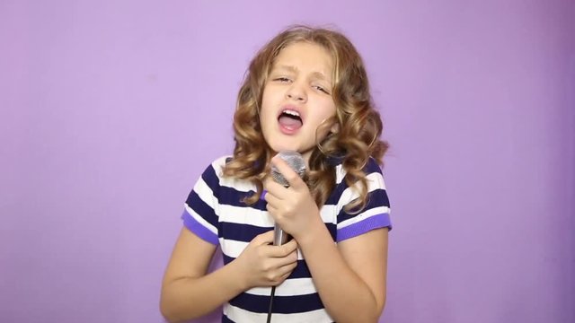 young girl with curly hair holding microphone, singing and funy dancing
