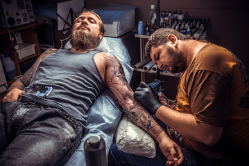 Fototapeta na wymiar Professional tattooist makes tattoo pictures in studio