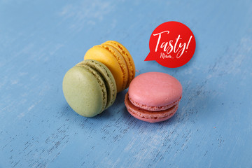 Macaroon cakes. Different types of macaron. Colorful almond cookies. Tasty speech bubble. On blue wooden rustic background.