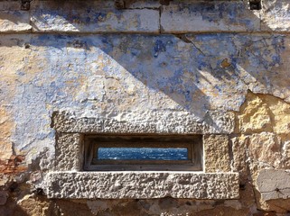 Granite window in old fortification with sea panorama, Caprera Island, Sardinia, Italy