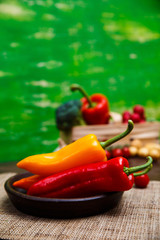 Sweet Peppers. Red and yellow vegetables. Fresh natural food in rustic bowl. Organic products on wooden table with sackcloth.