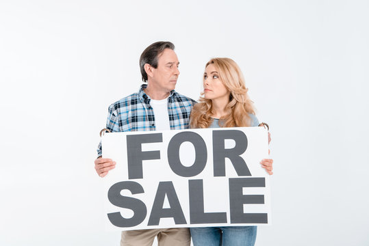 Front view of couple holding card with words for sale on white