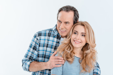 Front view of man and blonde woman embracing and smiling on white