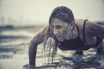  Strong athletic woman laughing with mud on her face crawling in mud or extreme sport with with grungy texture  © Paul