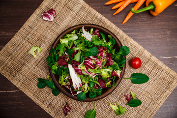 Provence salad. Leaves of endive or chicory, lamb and rose salad. Cherry tomato, pepper and carrot. Raw vegetables. On wooden table.
