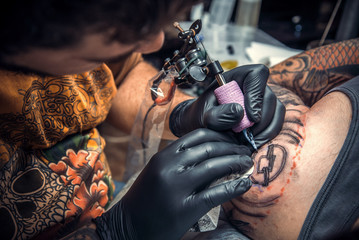Tattoo specialist making a tattoo in tattoo parlor
