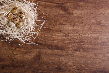 Quail eggs in straw nest. Natural organic eco food. Wooden rustic background.