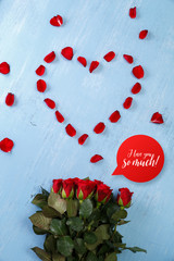 Heart of red rose petals on blue painted rustic background. Valentines day or love concept. I love you so much.
