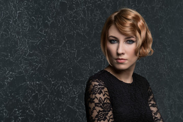 classical portrait of elegant blonde woman with a wave hairstyle and makeup on textural background