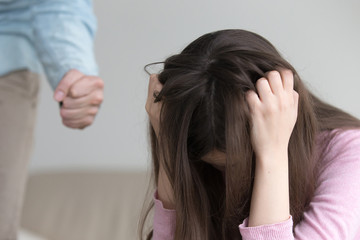 Fototapeta premium Young woman suffering from domestic violence and cruel abuse of women, furious guy intending to hit his girlfriend, showing fist, beating a girl, wife troubled with family tyranny and despotism