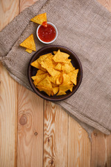 Nachos chips. Delicious salty tortilla with sweet salsa or chilli sauce on sackcloth background. Snack on rustic plate.