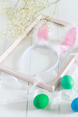 Easter bunny ears in a frame for pictures and colorful eggs on a white background. Selective color and space for text
