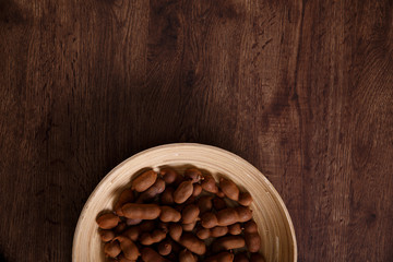 Sweet tamarind on grunge rustic wood background. Natural organic diet food with a lot of vitamins. Plate dish or bowl on wooden board.
