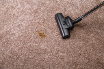 Vacuuming carpet with vacuum cleaner. Dirt on the rug. Housework service. Close up of the head of a...