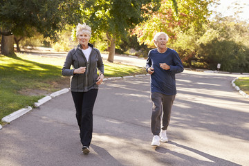 Senior Couple Jogging Through Park