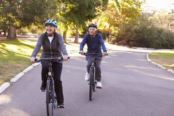 Front View Of Senior Couple Cycling Through Park Together