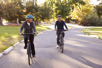 Naklejka premium Front View Of Senior Couple Cycling Through Park Together