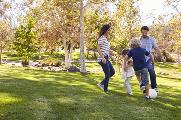 Family Playing Soccer In Park Together