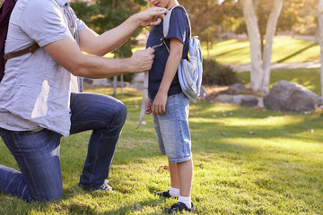 Father Fastening Son's Backpack As They Get Ready For Hike