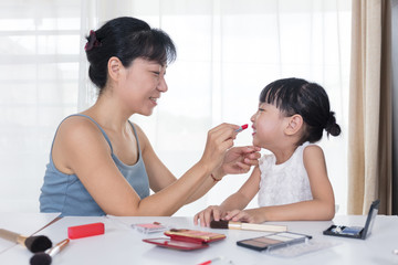 Asian Chinese mother and daughter having fun with cosmetics makeup