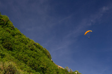 View of green hill and blue sky with paramotoring