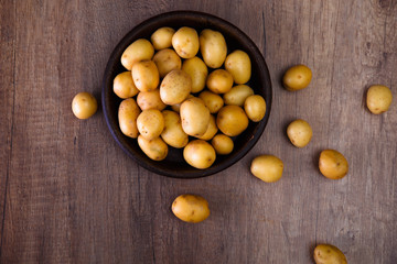 Potatoes in a rustic plate. Raw new potato. Fresh natural vegetables. Organic bio food on wooden table.