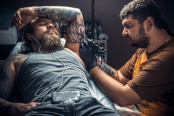 Tattoo master doing tattoo in tattoo studio
