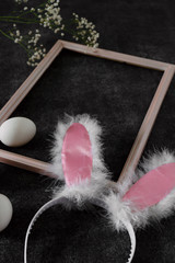 Easter bunny ears in a frame for pictures and eggs on a black background. Side view and space for text