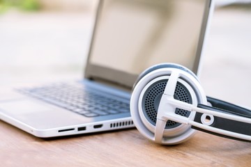 White headphones and laptop with screen on wooden desk with copy space