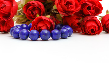 Beautiful high grade royal blue Lapis lazuli beads in bracelet with red roses on white background