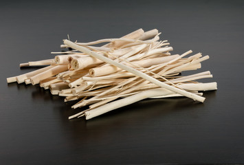 Pile of dry wooden sticks without bark on dark background
