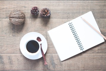 Cup of hot coffee with empty notebook on wooden table