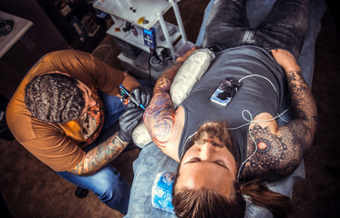 Fototapeta na wymiar Professional tattooist makes cool tattoo in studio