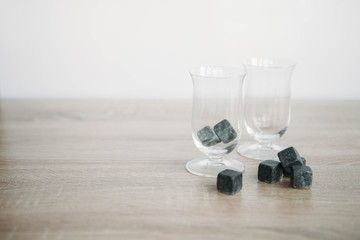 Stones for cooling whiskey and glases tulup on light wooden background