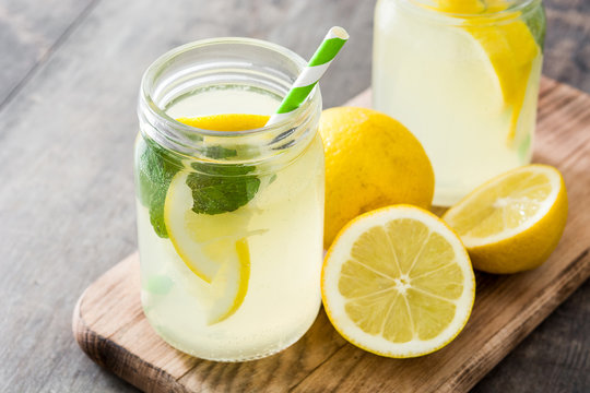 Lemonade drink in a jar glass on wooden background.
