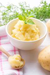 Mashed potato in a little bowl on white wooden background.