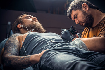 Fototapeta premium Tattoo master works in tattoo studio
