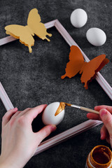 Workspace with easter decoration. Woman paints Easter eggs, slide view. Selective focus