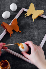 Workspace with easter decoration. Woman paints Easter eggs, slide view. Selective focus